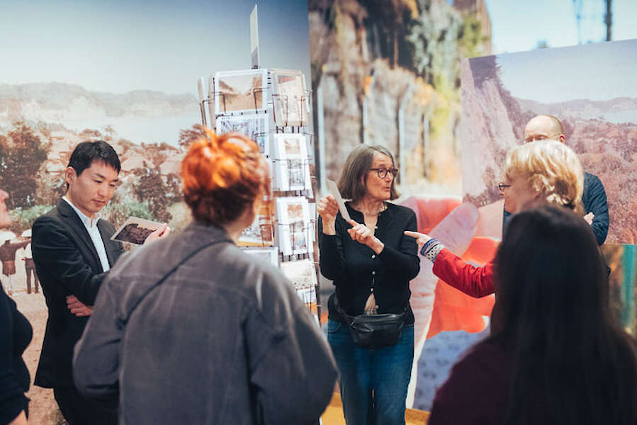 Besucher*innen am Postkartenständer in der Ausstellung.