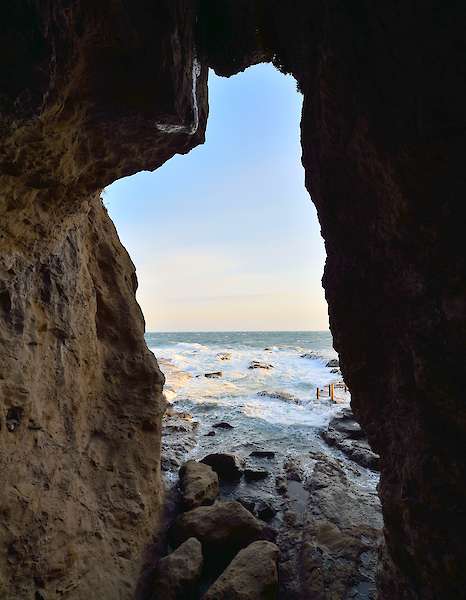 Foto einer Steinhöhle mit Öffnung zum Meer.